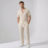 Man wearing a beige patterned shirt and pants against a plain background