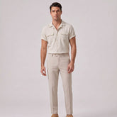 Man wearing a beige shirt and pants on a light gray background