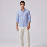 Man wearing a blue striped shirt and light-colored pants on a gray background