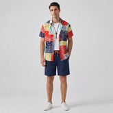 Man wearing a colorful patchwork shirt and navy shorts on a light gray background