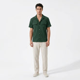 Man wearing a green shirt and beige pants on a white background