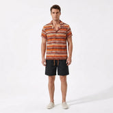 Man wearing a patterned shirt and black shorts on a white background