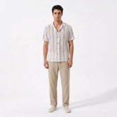 Man wearing a striped shirt and beige pants on a white background