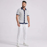 Man wearing a striped shirt and white pants on a light gray background