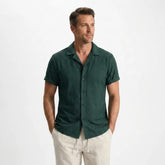 Man wearing a green shirt and beige pants on a white background