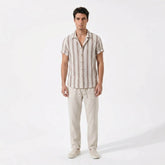 Man wearing a striped shirt and beige pants on a white background