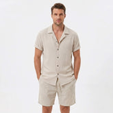 Man wearing a beige textured Cuban shirt and linen cotton drawstring shorts front view on plain background