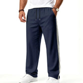 Man wearing MannerCo navy blue color-block drawstring jogger pants with contrast tape detail, front view