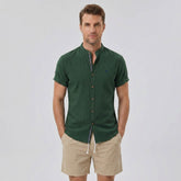 Man wearing a dark green linen look stand collar shirt and crinkle textured drawstring shorts front view