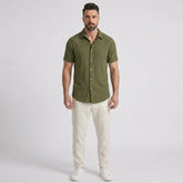 Man wearing a dark green waffle button up shirt and straight leg linen pants front view on plain background