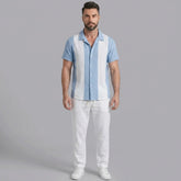 Man wearing a light blue patchwork cotton bowling shirt and straight leg linen pants front view on plain background