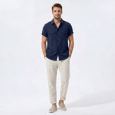 Man wearing a navy linen rayon blend pocket utility shirt and straight leg linen pants front view on plain background