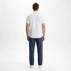 Back View of man wearing a black and white striped shirt with white pants on a gray background