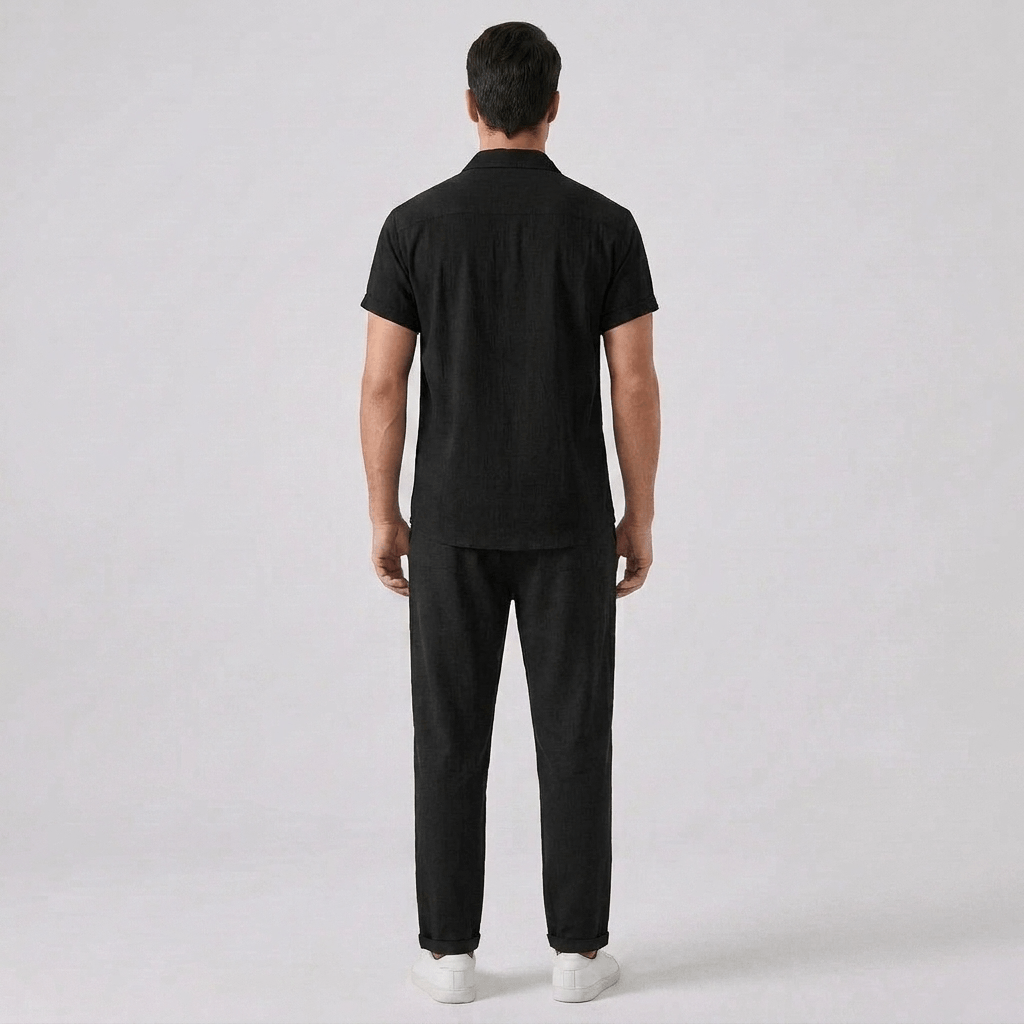 Back view of man wearing a black outfit against a gray background