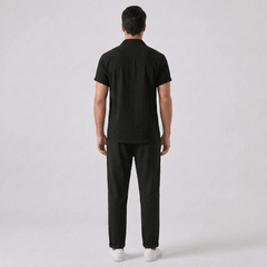 Back view of man wearing a black outfit against a gray background