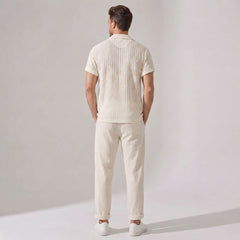 Back view of man wearing a cream-colored outfit with a shirt and pants on a plain background