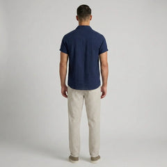Back view of man wearing a navy blue polo shirt and beige striped pants on a light gray background