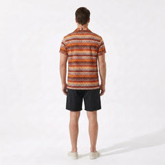 Man wearing a patterned shirt and black shorts on a white background