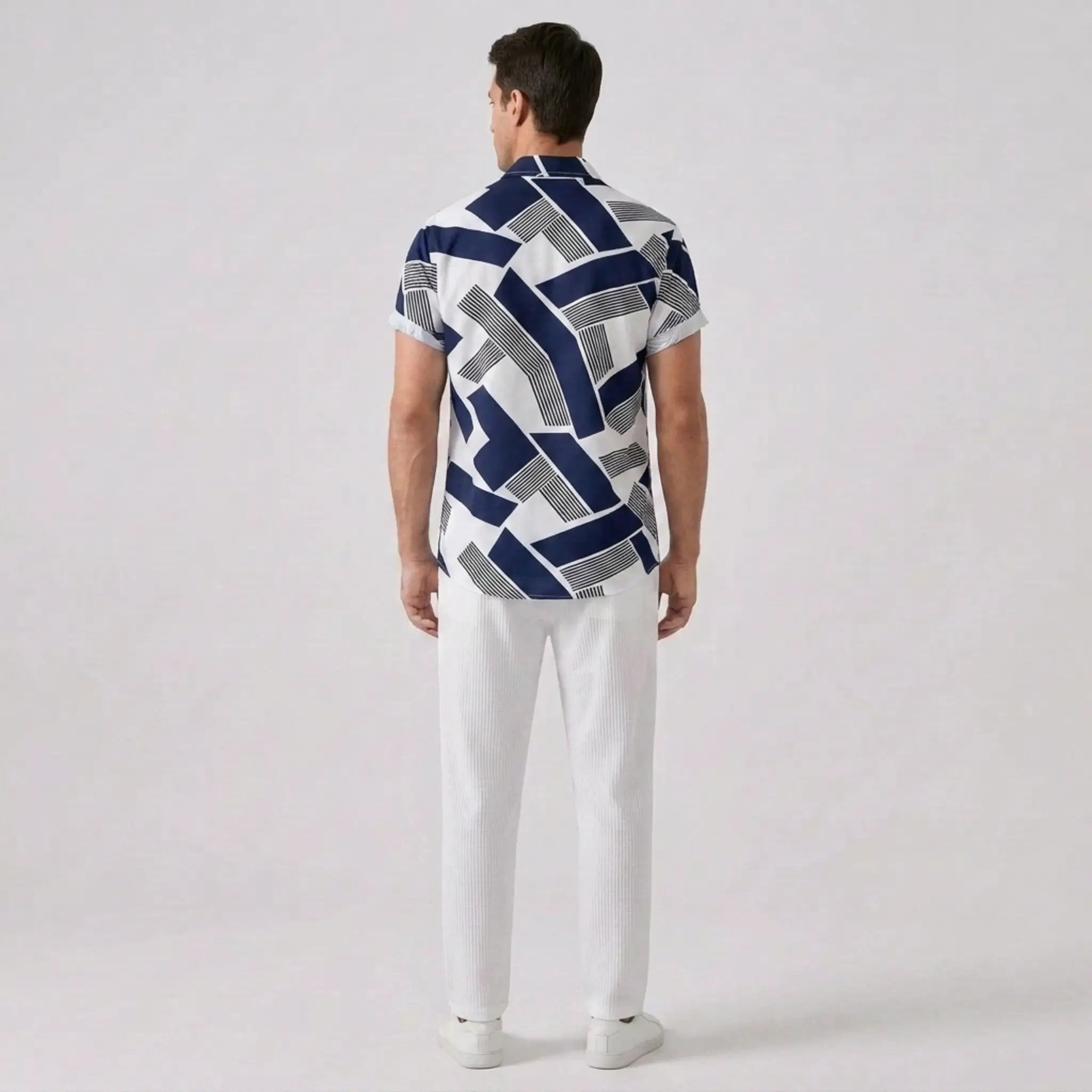 Back view of man wearing a patterned shirt and white pants on a plain background
