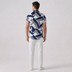 Back view of man wearing a patterned shirt and white pants on a plain background