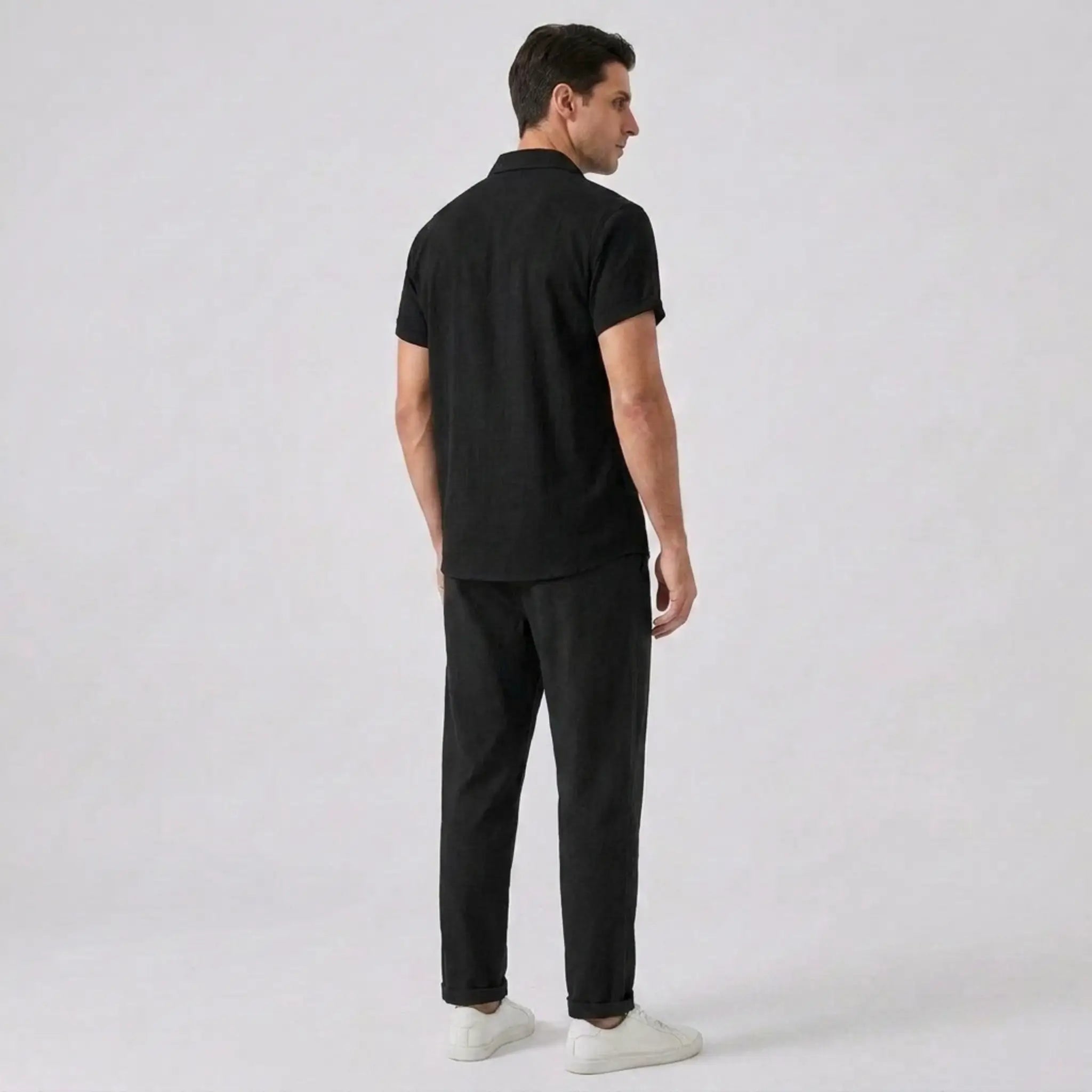 Back view of man wearing a shirt with black pants on a gray background