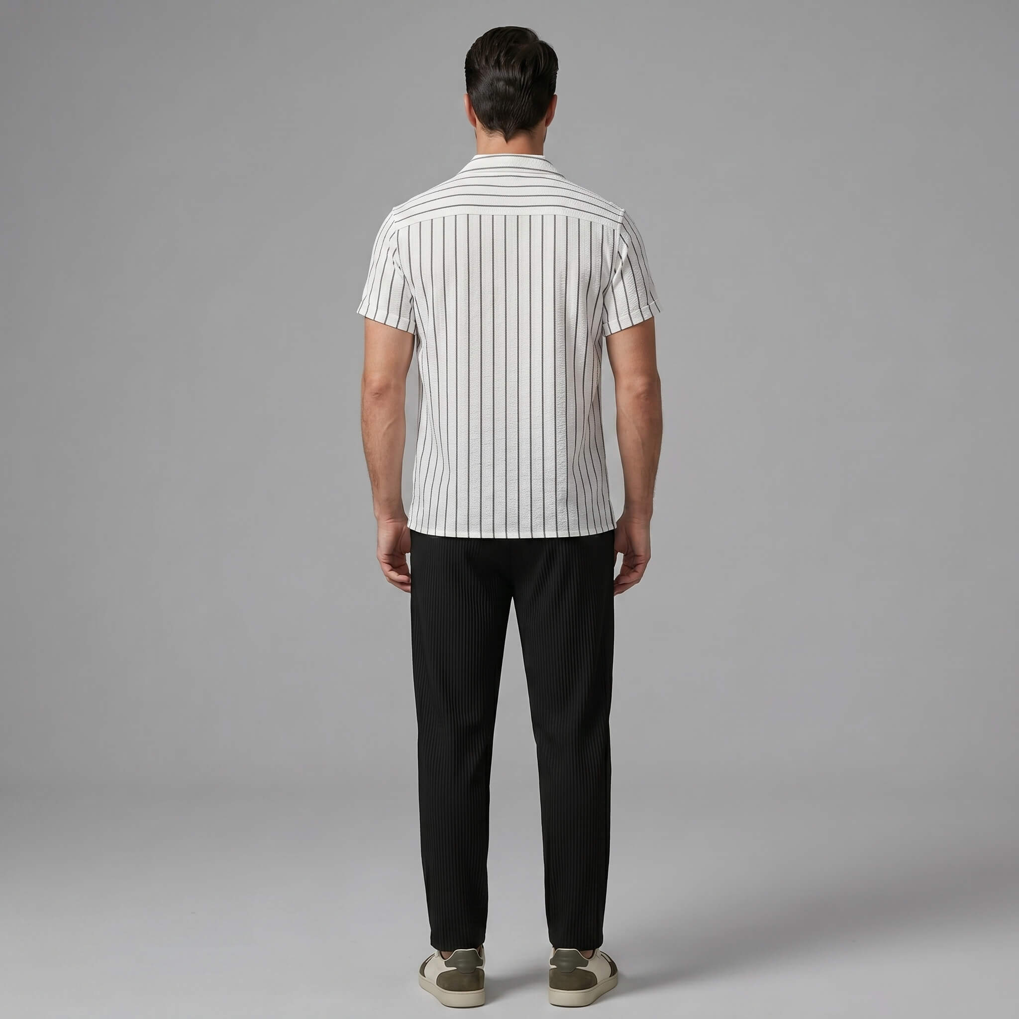 Back view of man wearing a white striped shirt and black pants on a gray background