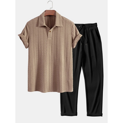 Beige short-sleeve shirt and black pants on a hanger against a white background
