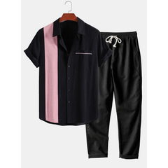Black and pink shirt with black pants on a hanger against a white background