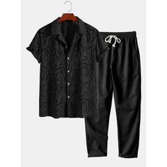 Black patterned shirt and pants set on a hanger against a white background