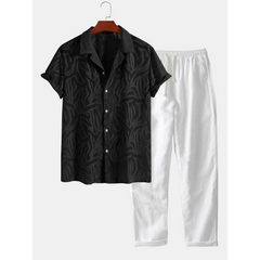 Black patterned shirt and white pants on a hanger against a white background
