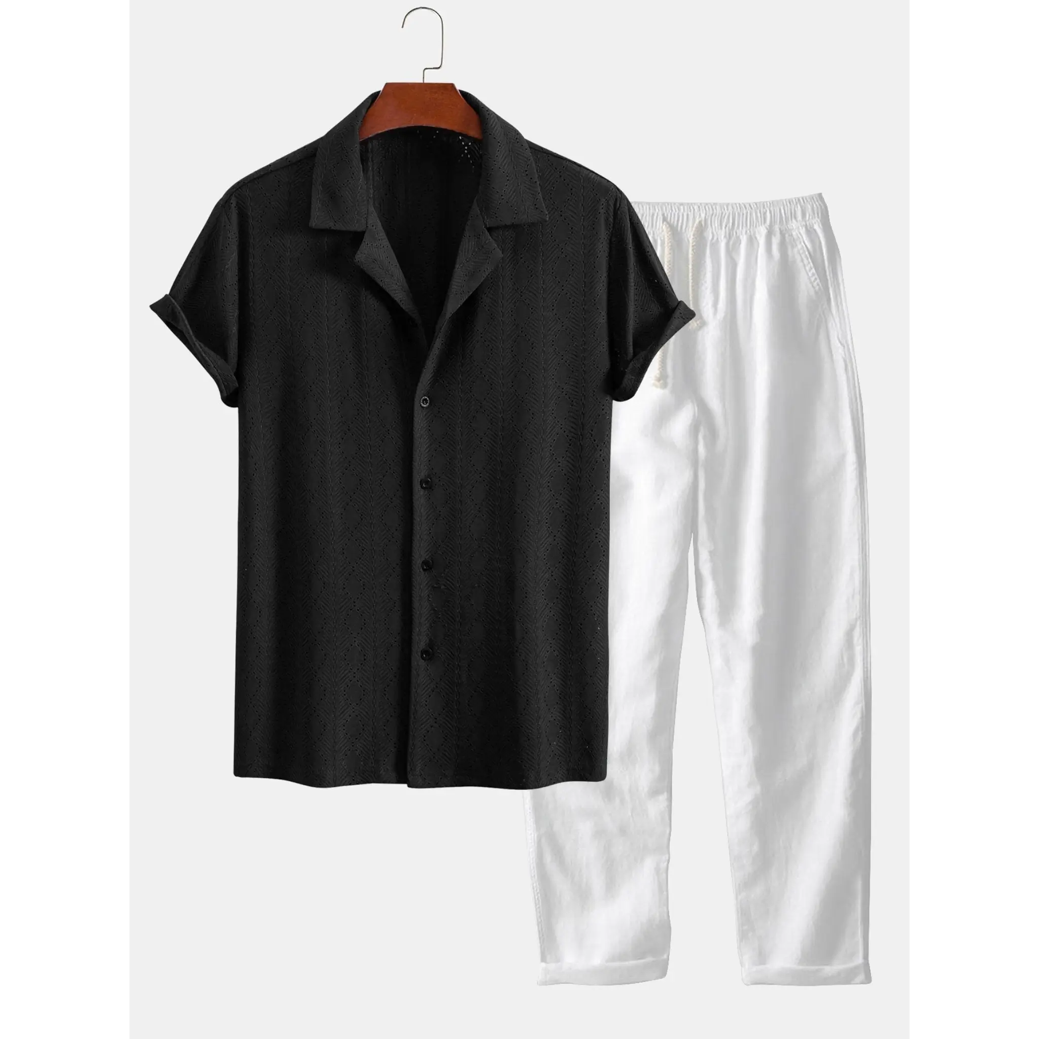 Black shirt and white pants on a hanger against a white background