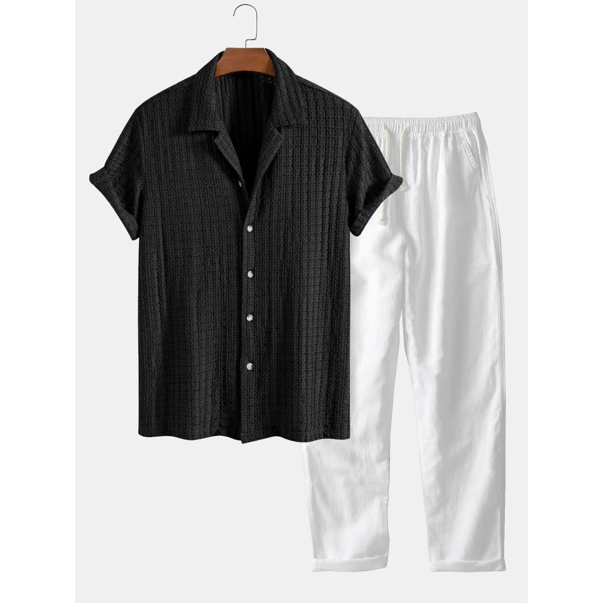 Black short-sleeve shirt and white pants on a hanger against a white background