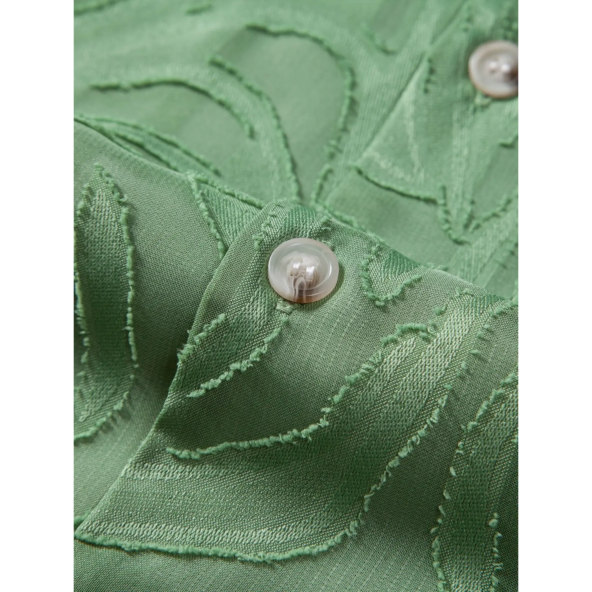 Close-up of green jacquard fabric texture with button