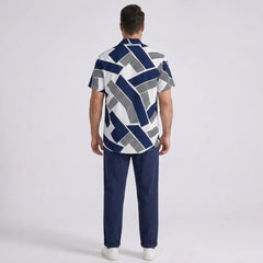 Man back view wearing a patterned shirt and dark pants on a light gray background