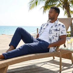 Man lounging on a beach chair by the ocean with palm trees in the background