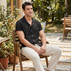 Man sitting on a wooden chair outdoors in a garden setting