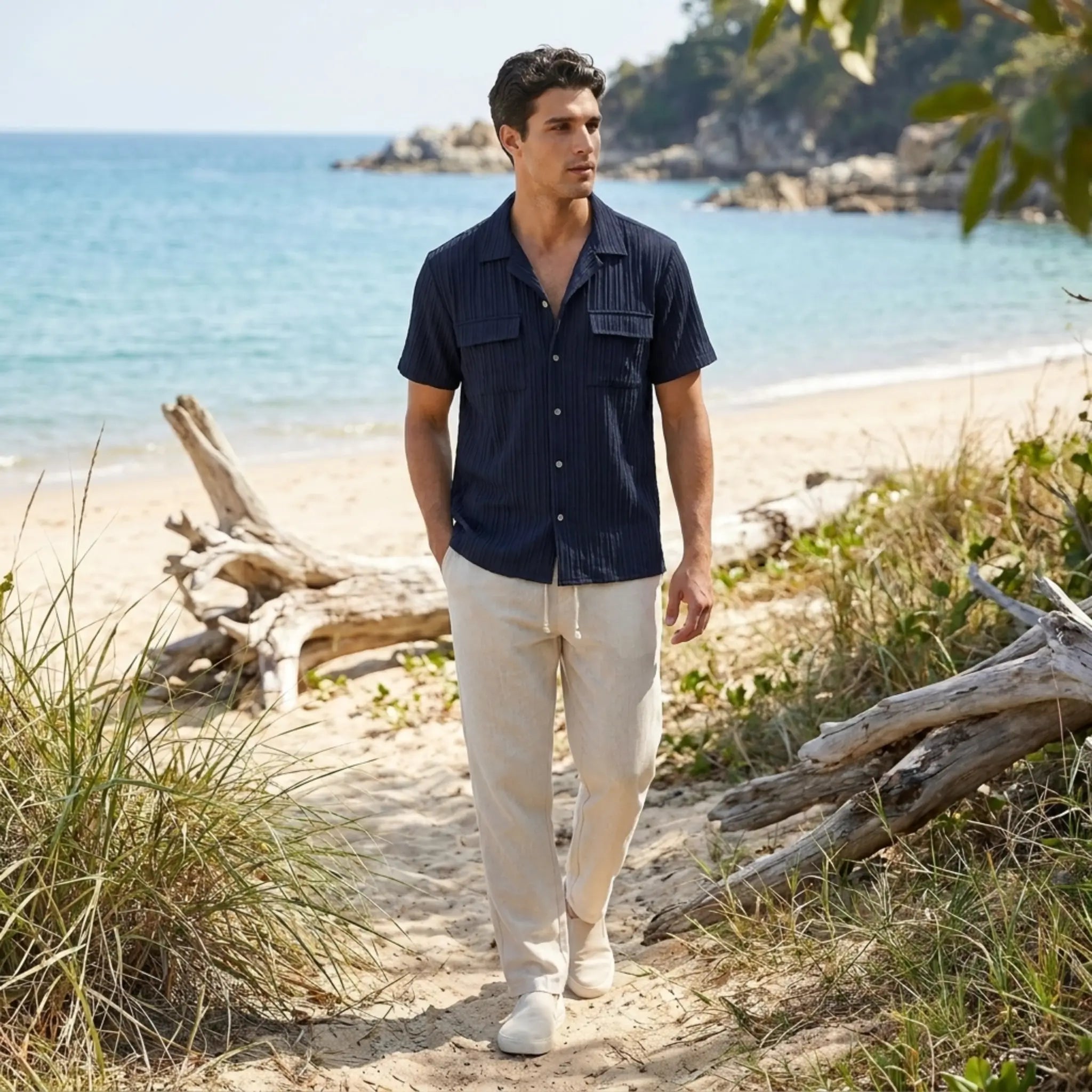 Man walking on a beach with ocean and rocks in the background
