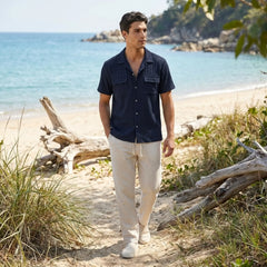 Man walking on a beach with ocean and rocks in the background