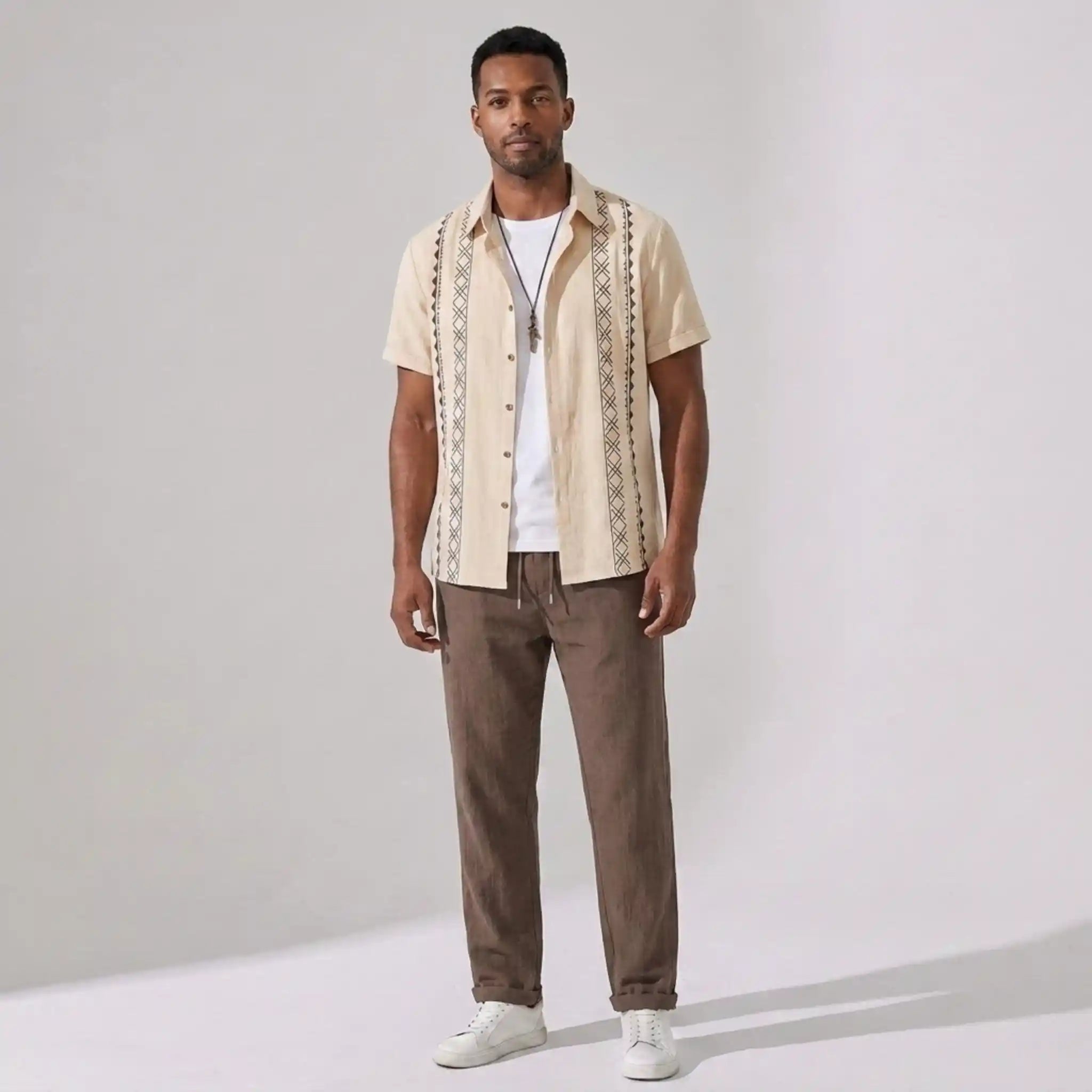 Man wearing a beige patterned shirt and pants on a gray background
