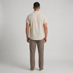 Man wearing a beige shirt and striped pants against a plain background