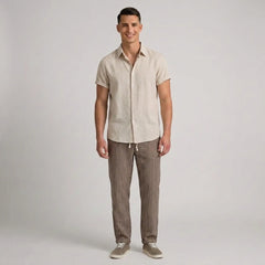 Man wearing a beige shirt and striped pants on a plain background