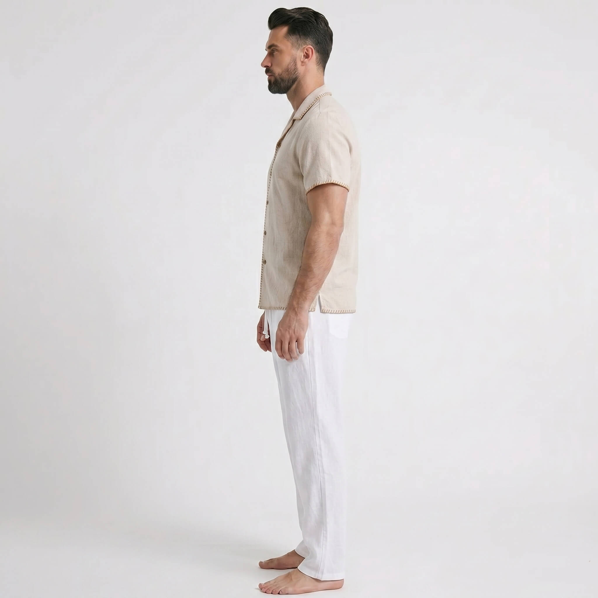 Man wearing a beige shirt and white pants on a plain background