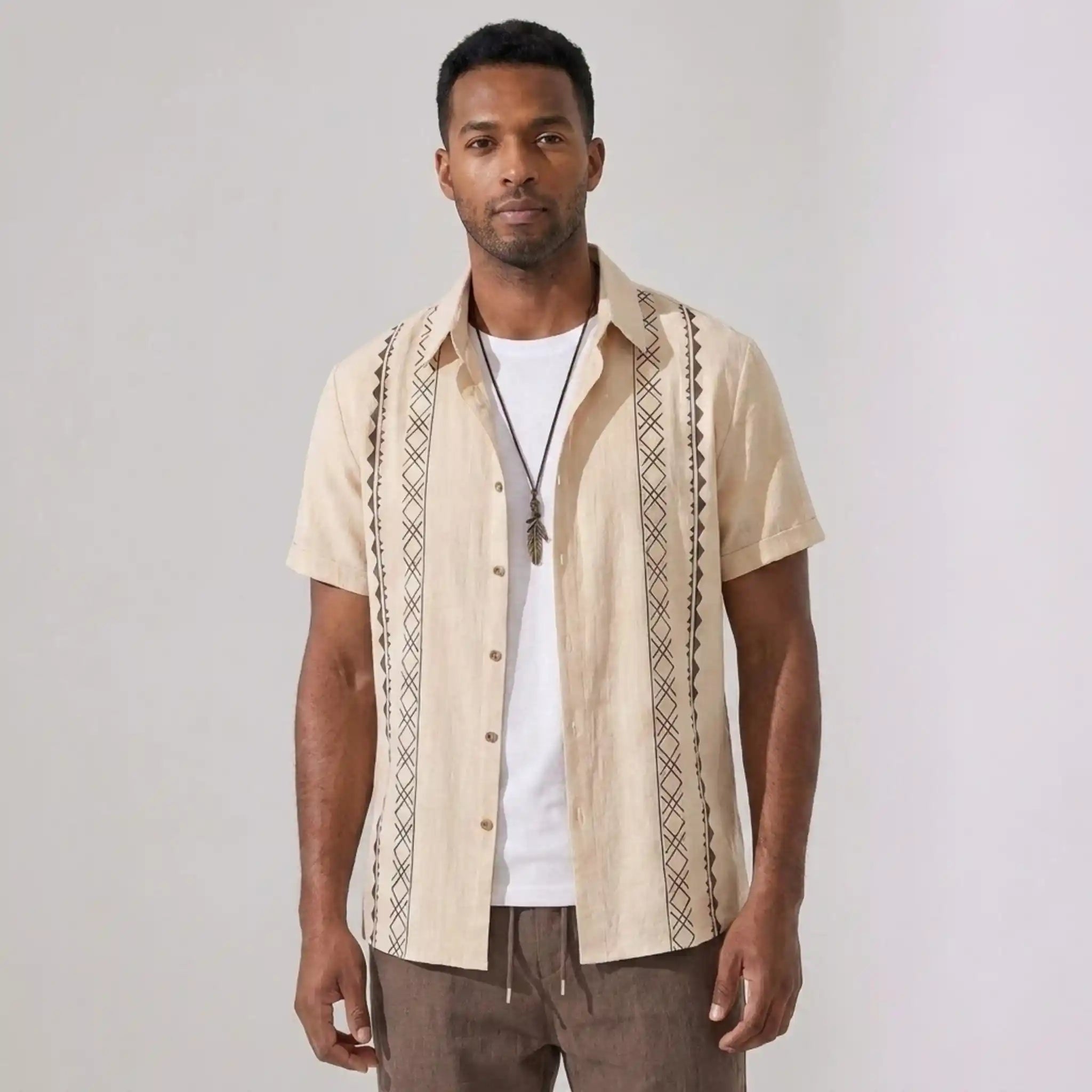 Man wearing a beige outfit standing against a plain background