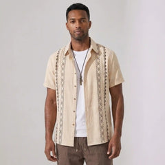 Man wearing a beige outfit standing against a plain background