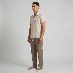 Man wearing a beige shirt and striped pants on a plain background