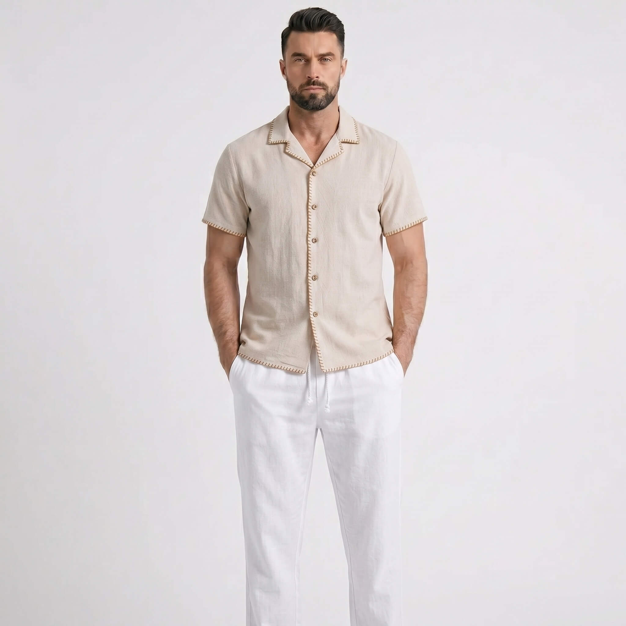 Man wearing a beige short-sleeve shirt and white pants on a light gray background