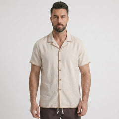 Man wearing a beige short-sleeve shirt with buttons on a light gray background