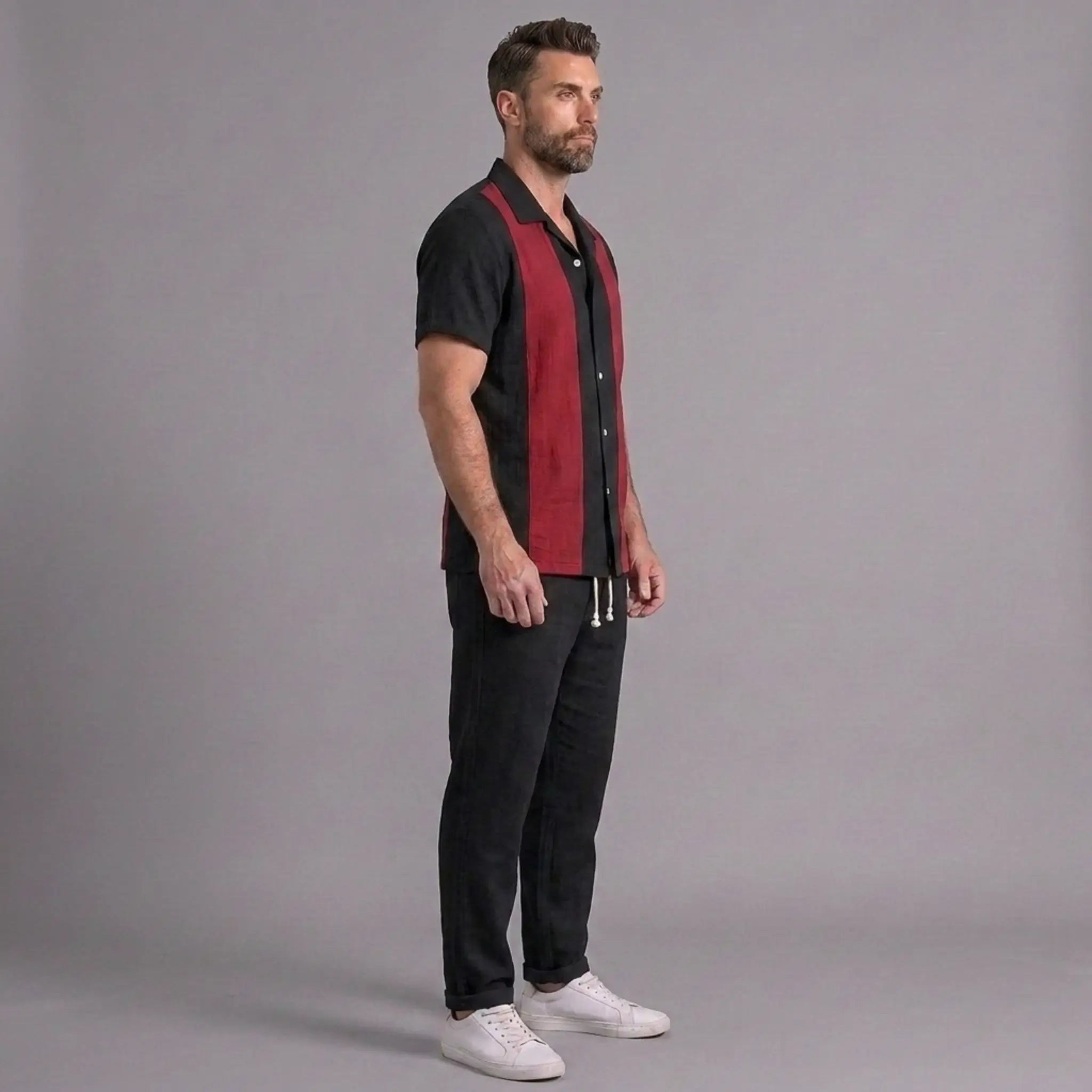 Man wearing a black and red shirt with black pants on a gray background