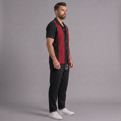Man wearing a black and red shirt with black pants on a gray background
