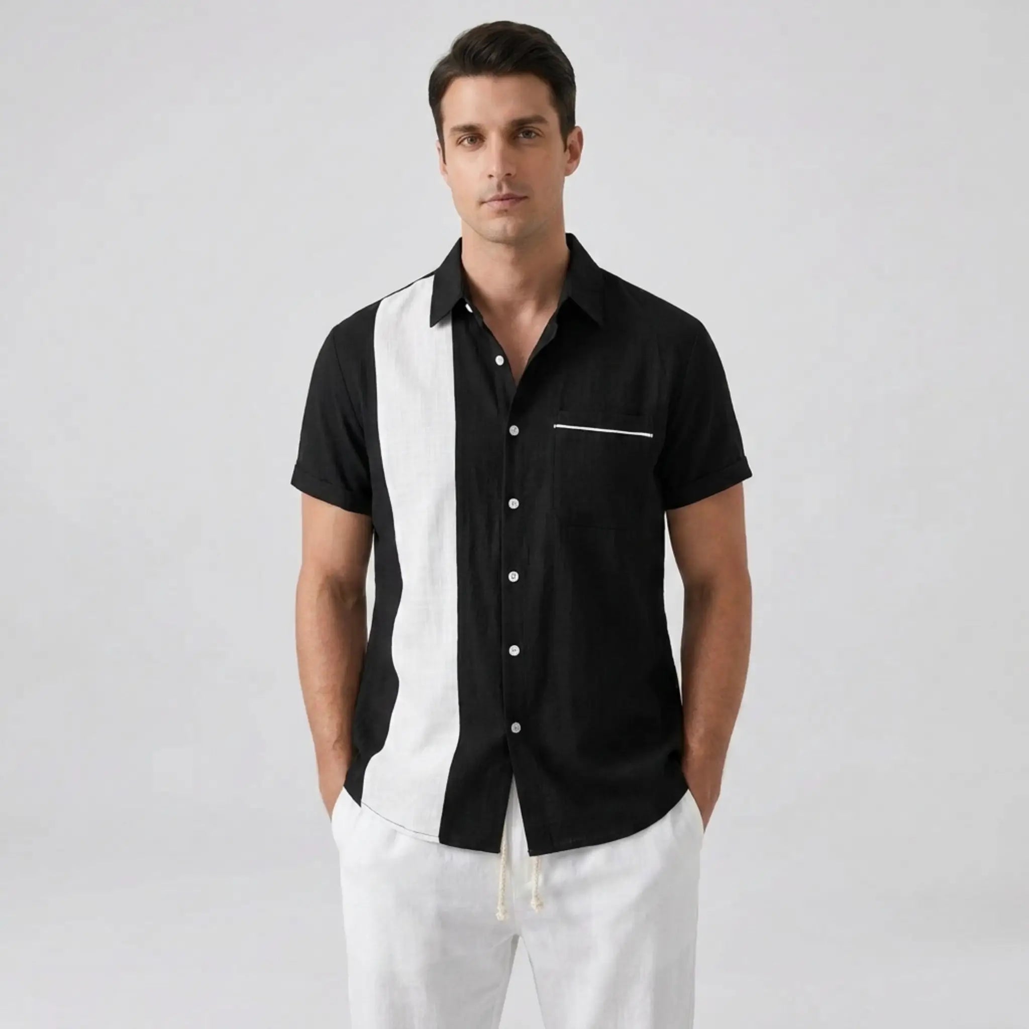 Man wearing a black and white striped shirt with white pants on a gray background